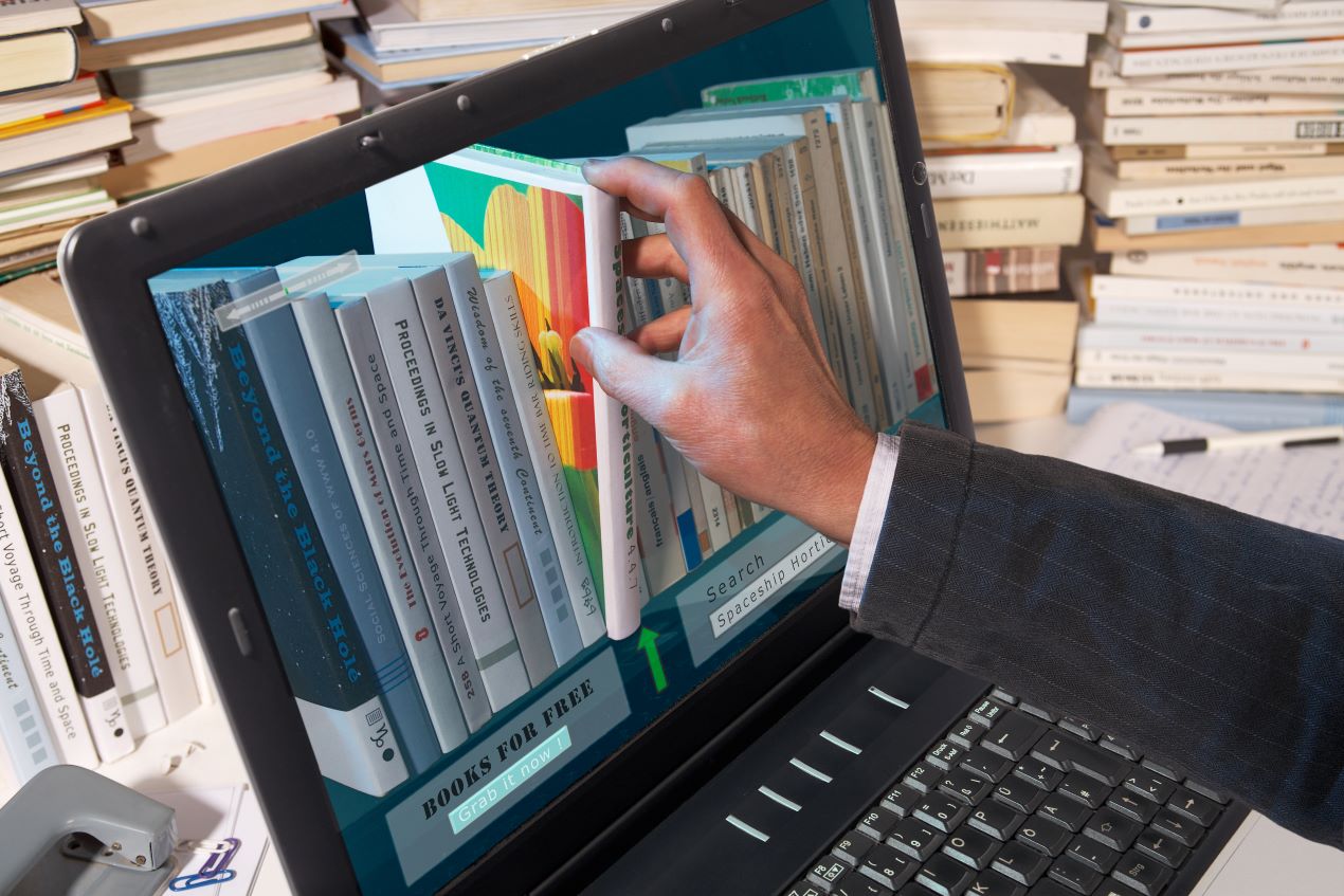 Eine Hand greift durch einen Laptop zu digitalen Bücherregalen, symbolisiert die Automatisierung der Warenwirtschaft im Buchhandel.